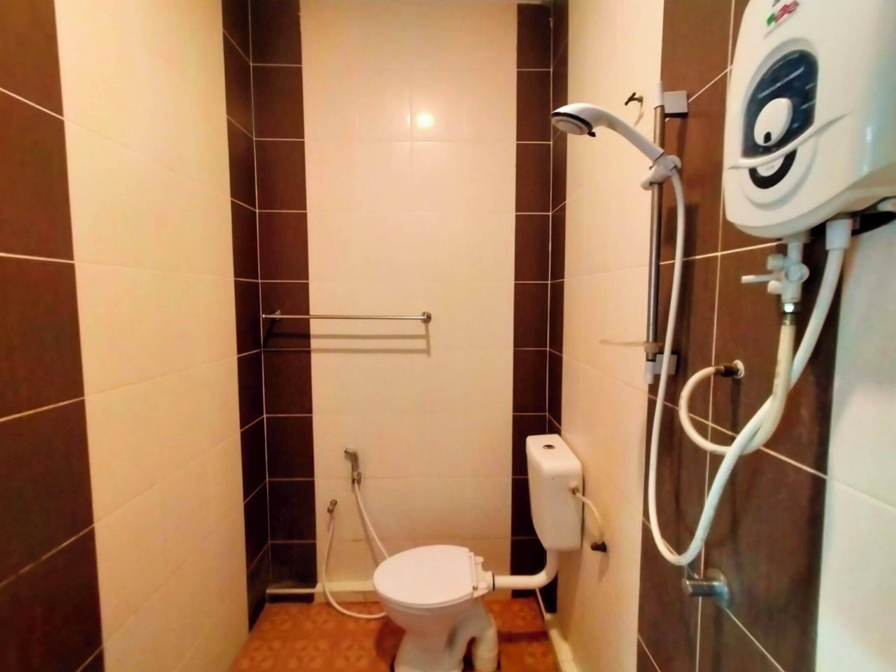 Ein kleines Badezimmer mit Toilette, Handbrause und Toilettenpapierhalter.