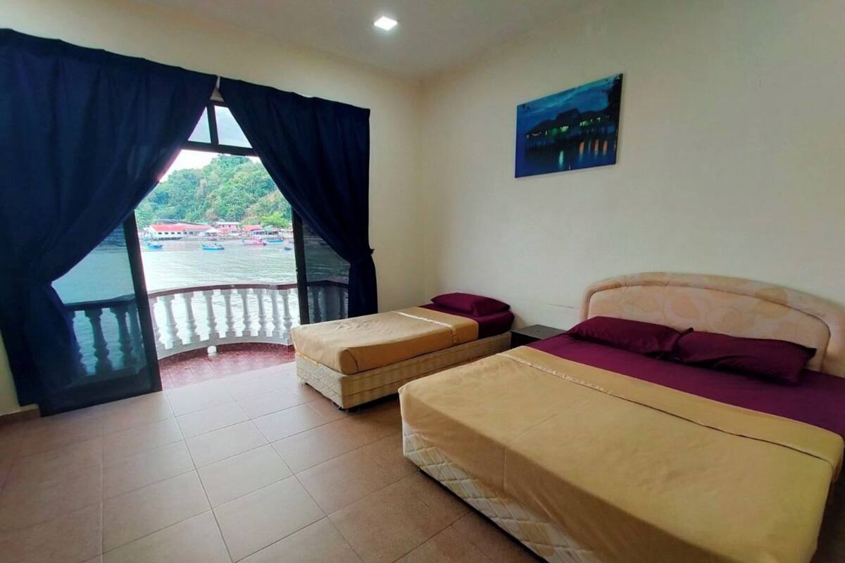 Ein Zimmer mit zwei Betten, einem Balkon mit Blick auf das Wasser und einem Bild an der Wand.