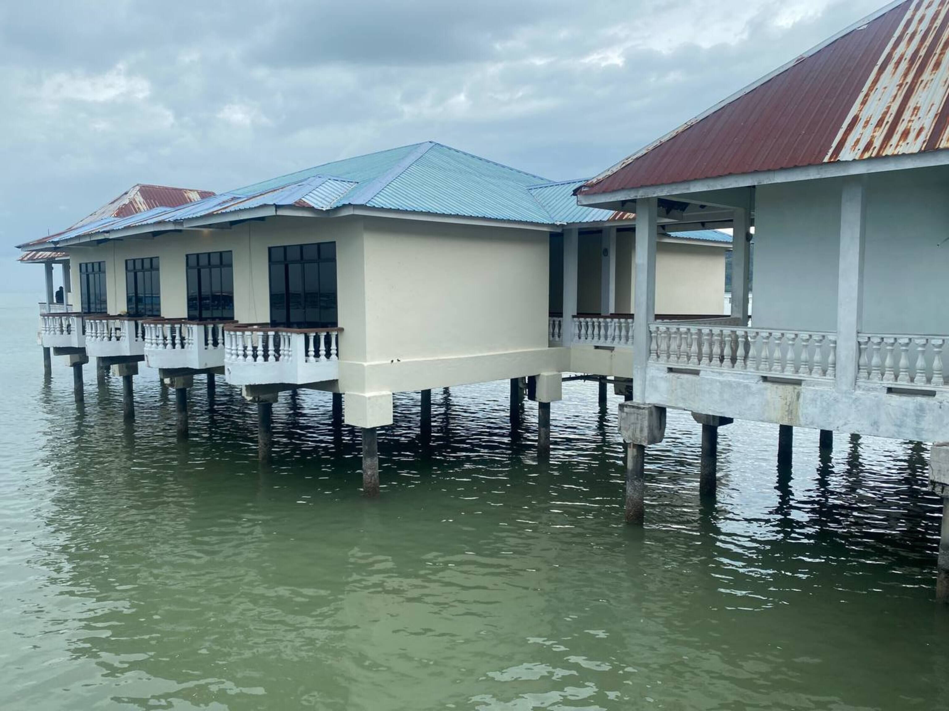 A waterfront hotel with multiple overwater bungalows, each featuring a balcony and a covered area.