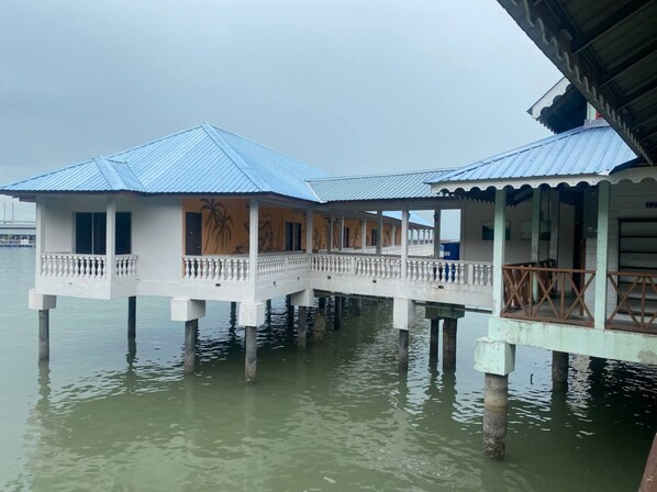 A waterfront building with a covered walkway over water, supported by pillars. - Capital O 91118 Chalet Seri Idaman (Batu Maung)