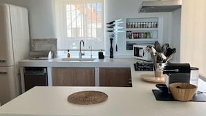 Una cocina moderna con una isla central, electrodomésticos integrados y un ventanal que proporciona luz natural.