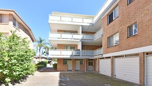 A multi-story residential building with a central courtyard, balconies, and garage doors. - Shoal Bay Sands - 2-Bedroom (Nelson Bay)