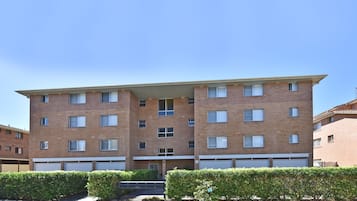 A multi-story residential building with a flat roof, multiple windows, and a visible garage door.