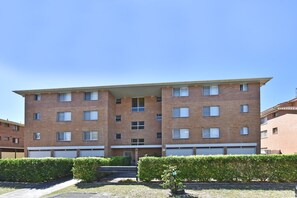 A multi-story residential building with a flat roof, multiple windows, and a visible garage door.
