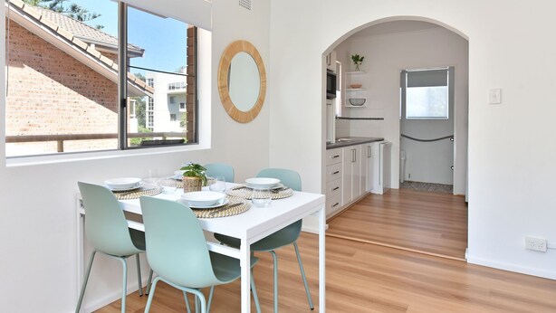 A modern kitchen with white cabinets, a stainless steel refrigerator, and a window overlooking a brick building. - Shoal Bay Sands - 2-Bedroom (Nelson Bay)