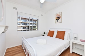 Een moderne slaapkamer met een bed, een nachtkastje, een raam en een wanddecoratie.