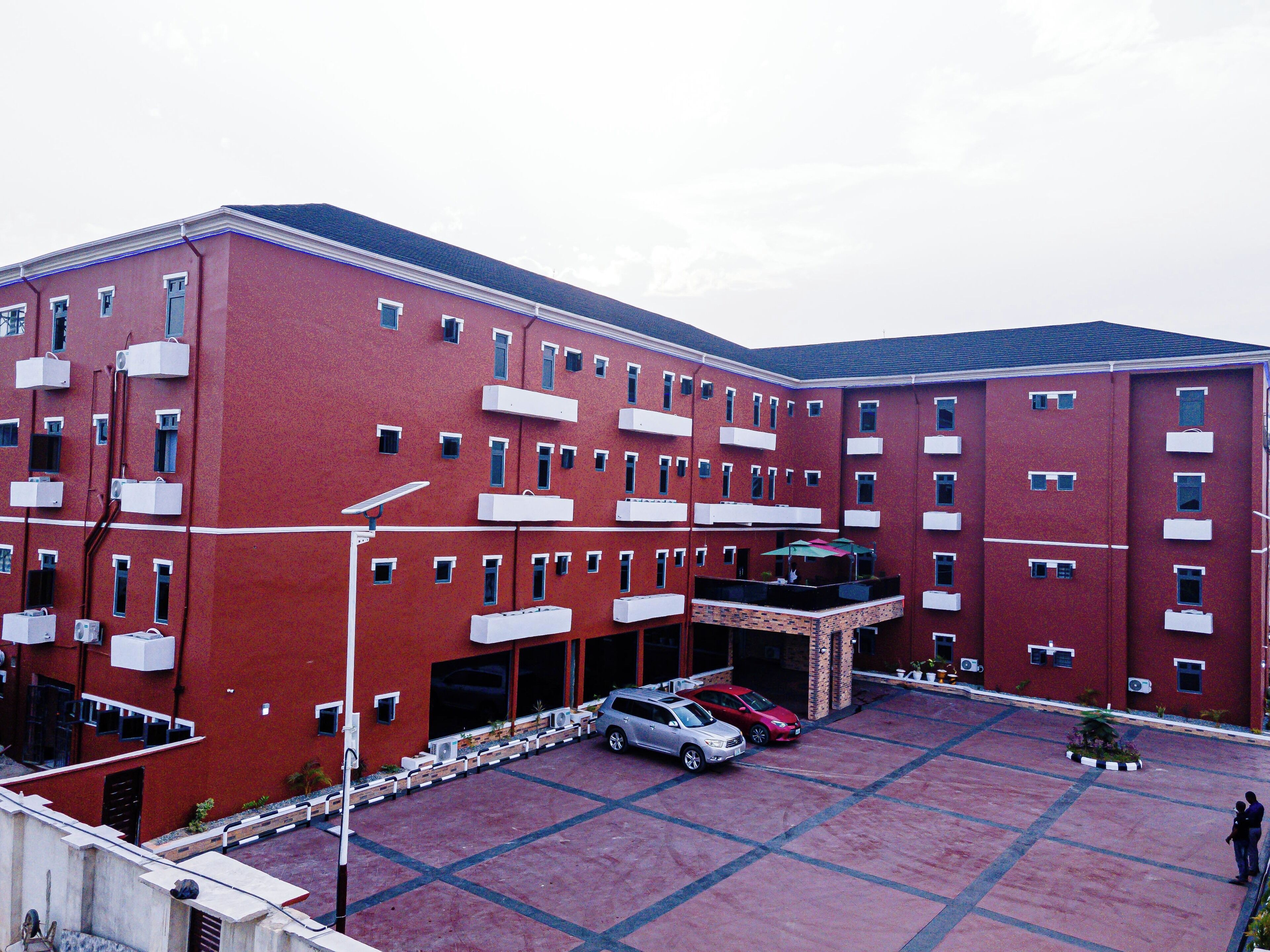 A multi-story red building with a parking area in front.