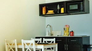 A small kitchen with a microwave, sink, and a white dining table with chairs.