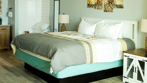 A bedroom with a bed, bedside tables, a nightstand, a mirror, and a painting on the wall.