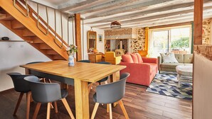 Un tavolo da pranzo in legno con sedie, una scala, un divano e un tappeto decorato.