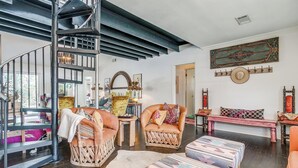 A spacious living room with a spiral staircase, wooden furniture, and a large decorative mirror. - Private Pool Oasis | Spa & Game Room • 12 (Fort Worth)