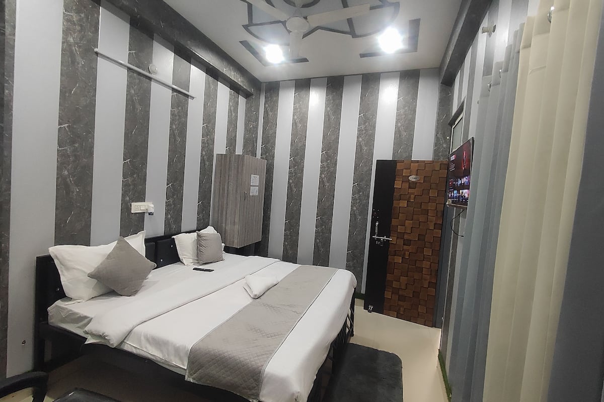 A modern bedroom with a bed, bedside tables, a wardrobe, and a television on the wall.