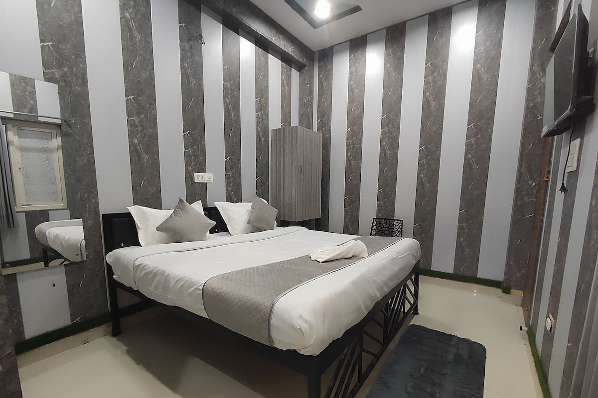 A neatly arranged bedroom with a bed, bedside tables, a wardrobe, and a small desk.
