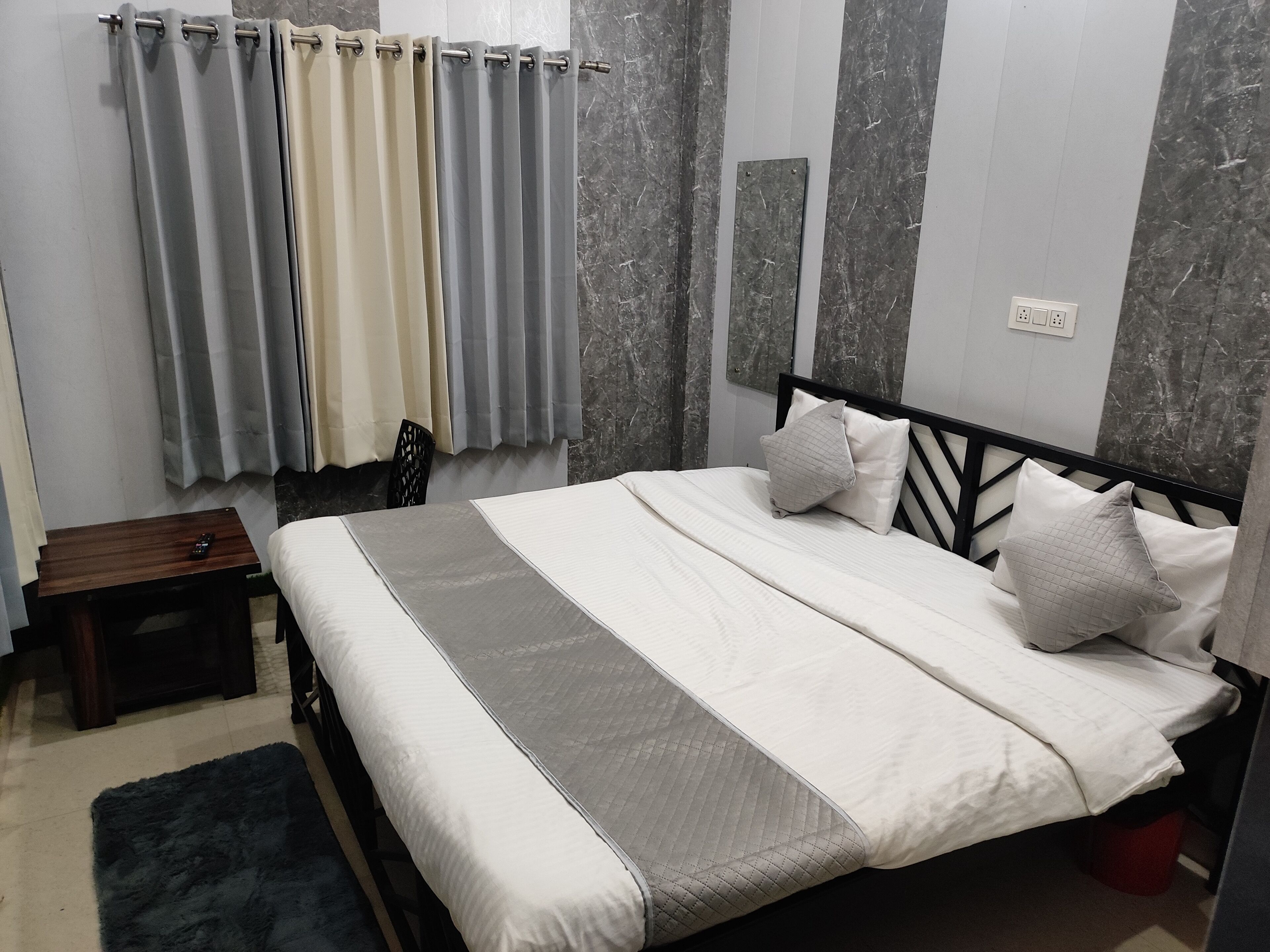Ein ordentlich eingerichtetes Schlafzimmer mit Bett, Nachttisch, Stuhl und einem Fenster mit Vorhängen.