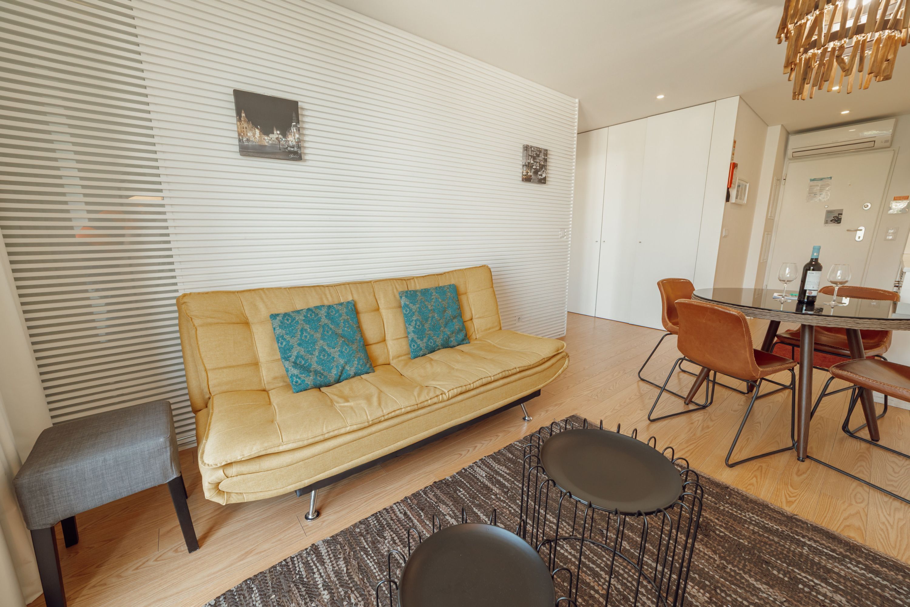 A modern living room with a sofa, a dining table, and chairs.