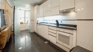 Una cocina moderna con armarios blancos, encimera negra y horno empotrado.