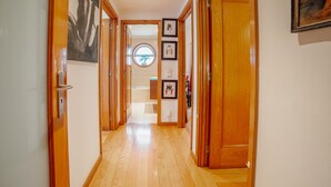 Un pasillo con puertas de madera, una escalera y cuadros enmarcados en las paredes.