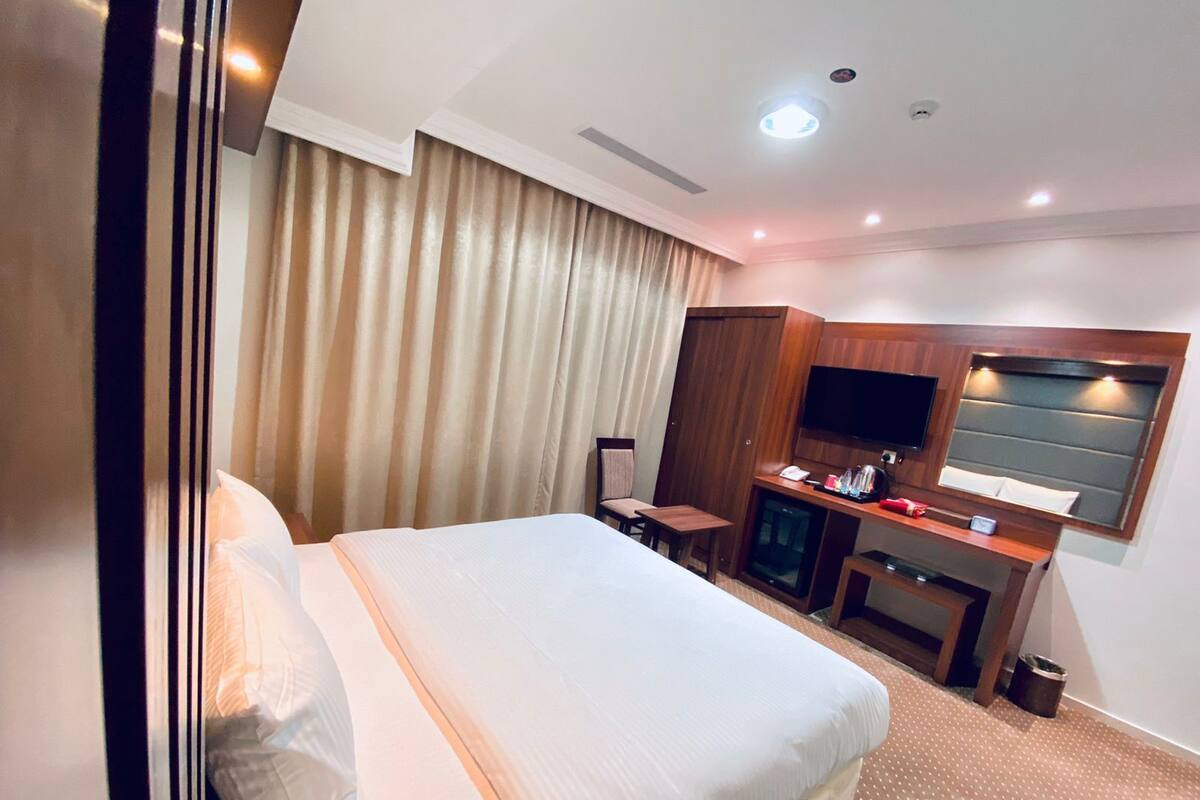 Una habitación de hotel con una cama grande, televisión, escritorio y espejo.