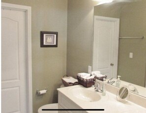 A bathroom with a white sink, a mirror, a framed picture on the wall, and a toilet. - Masters Golf Tournament Within 6 Miles - Convenient, Beautiful, Spacious (Augusta)