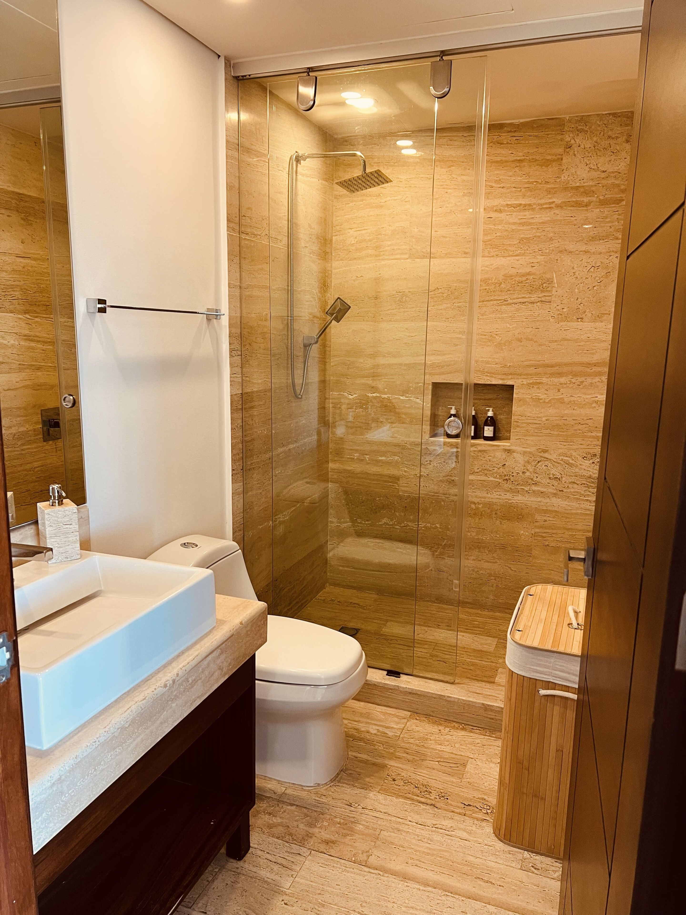 Ein modernes Badezimmer mit einer Duschkabine, einem weißen Waschbecken und einer Toilette.