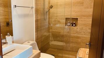 Ein modernes Badezimmer mit einer Duschkabine, einem weißen Waschbecken und einer Toilette.