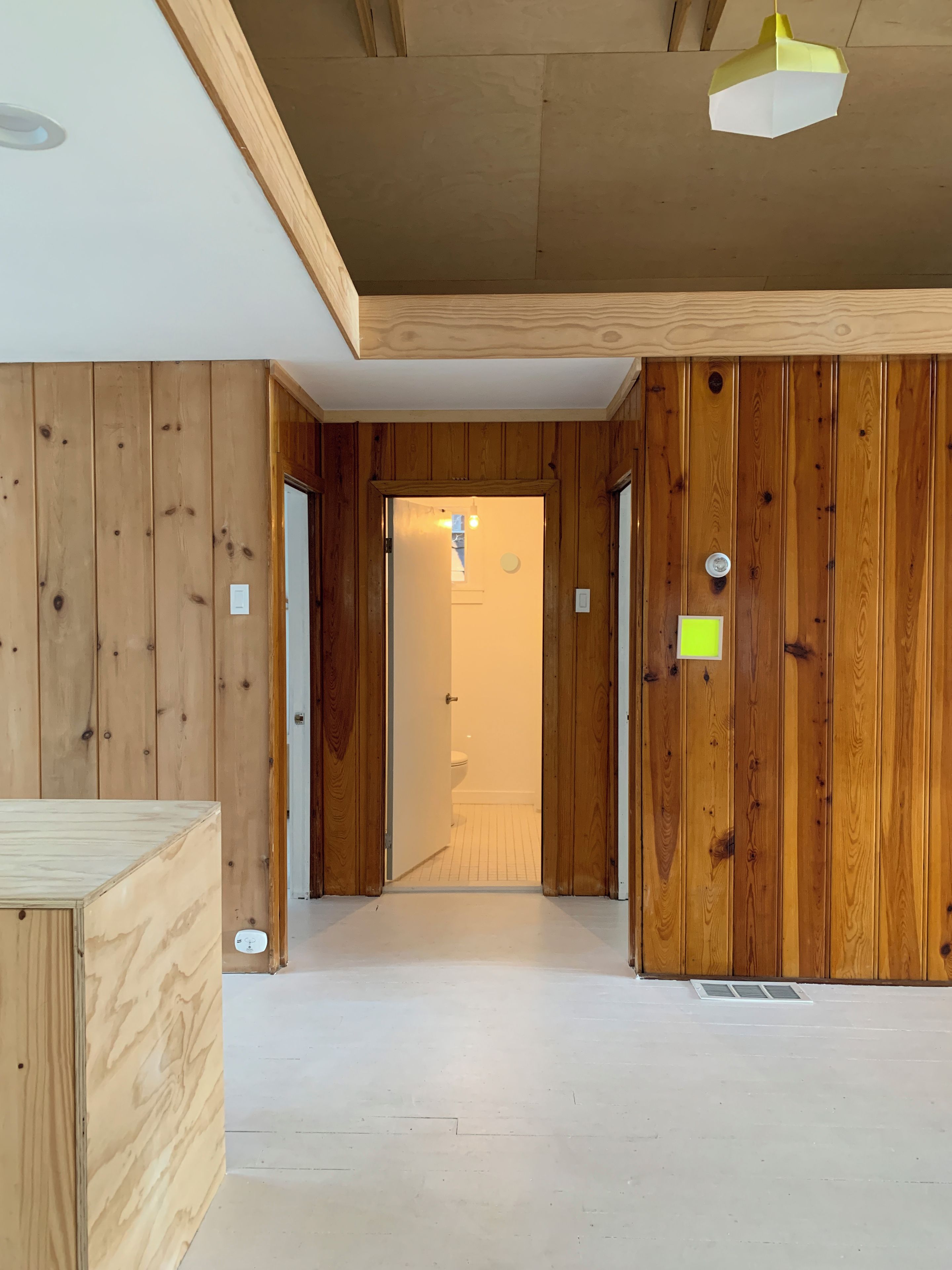 Un couloir aux murs en bois et une porte donnant accès à une salle de bain.