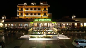 A hotel with a prominent entrance, multiple floors, and a well-lit facade. - HOTEL GRAND HAVELI (Umargam)