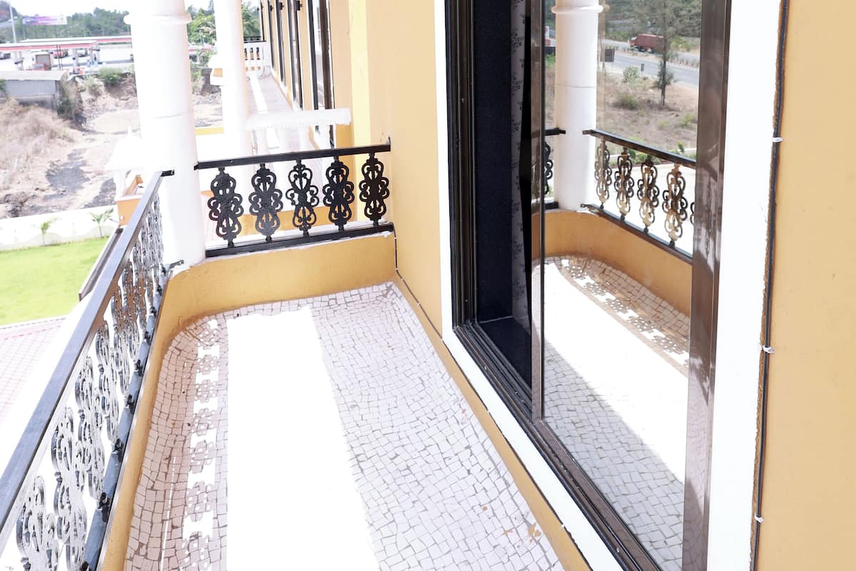 A balcony with a tiled floor, white columns, and a black railing.