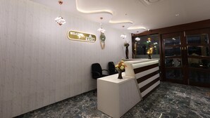 A reception area with a modern design, featuring a reception desk, chairs, a welcome sign, and decorative lighting. - HOTEL GRAND HAVELI (Umargam)