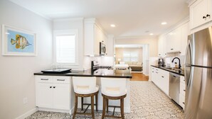A modern kitchen with white cabinetry, a stainless steel refrigerator, and a patterned floor.