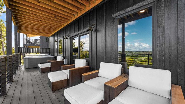 A covered outdoor seating area with wicker furniture and a hot tub. - The Back Nine Retreat by Avantstay Private Golf Sim, Firepit & Mountain Views Near Dollywood (Sevierville)