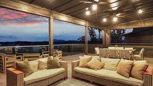 An outdoor patio with wicker furniture, a dining table, and a view of the landscape. - The Back Nine Retreat by Avantstay Private Golf Sim, Firepit & Mountain Views Near Dollywood (Sevierville)