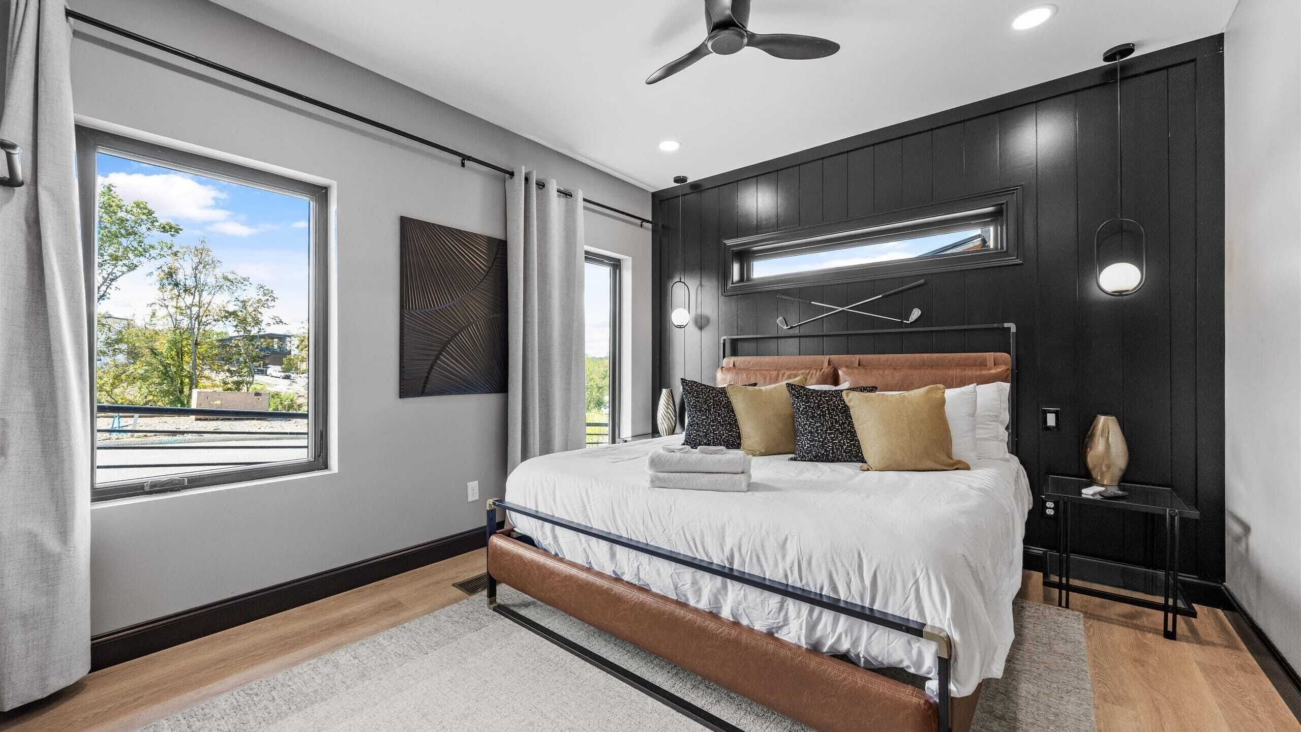 Une chambre moderne avec un grand lit, un ventilateur de plafond et une vue sur l’extérieur.
