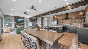 A modern kitchen with a wooden dining table, bar stools, and a built-in oven.