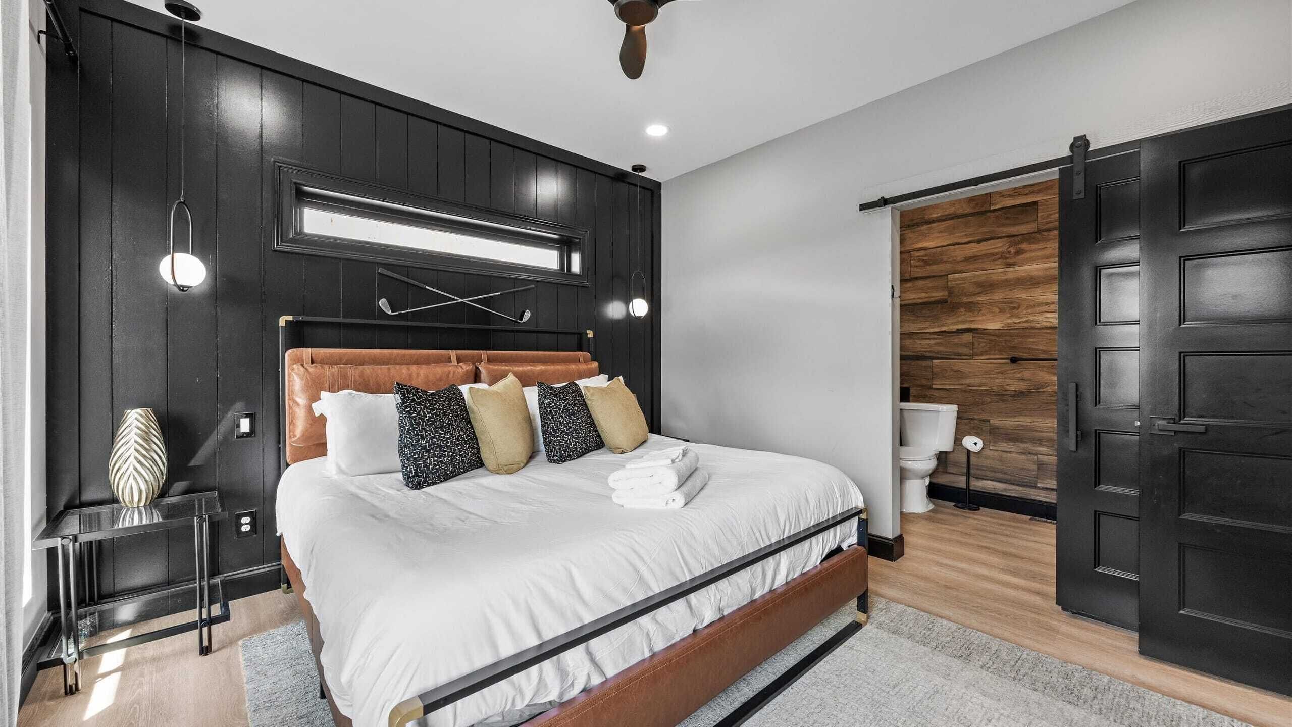 A modern bedroom with a large bed, a wooden door, and a built-in toilet.