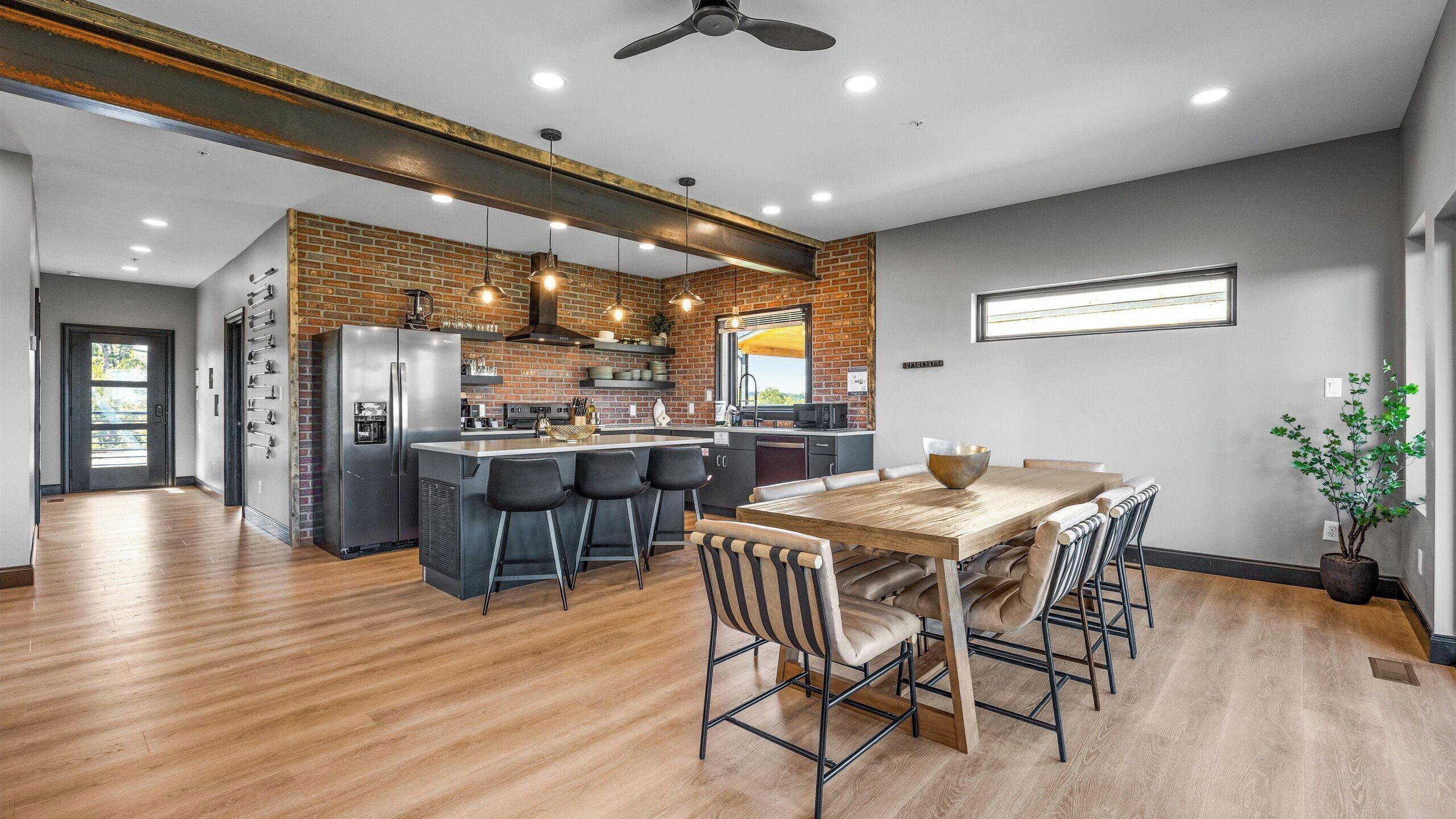 A modern kitchen with a central island, bar stools, and a dining table with chairs.