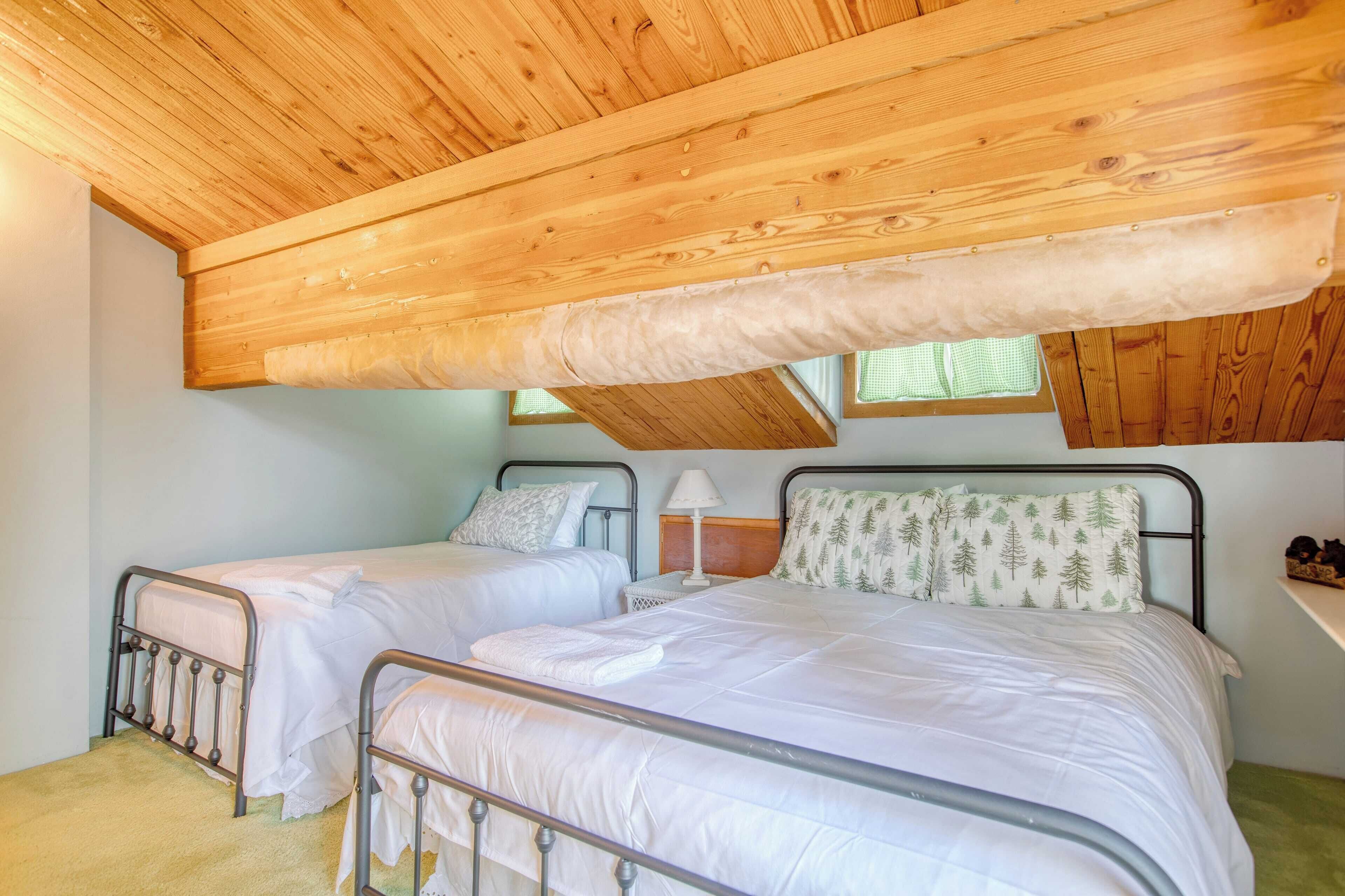 Ein Schlafzimmer mit zwei Betten, Holzbalkendecke und einem Fenster.