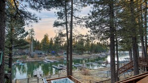 A deck with a hot tub overlooking a lake with docks and boats.