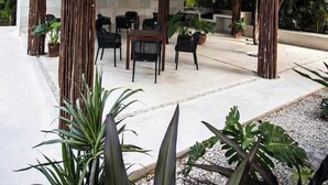 A covered outdoor seating area with a ceiling fan, surrounded by wooden pillars and potted plants. - Beautiful apartment for rent Great location close to the beach, walking distance (Playa del Carmen)