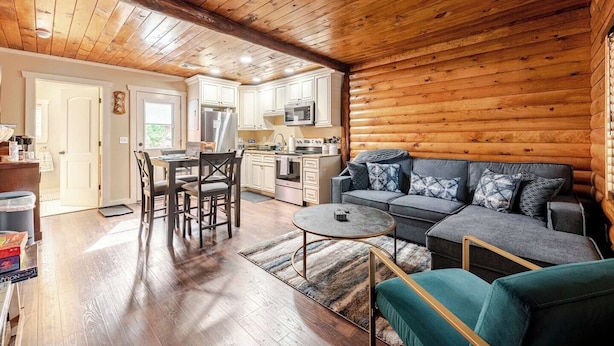 A cozy log cabin interior with a dining area, kitchen, and living room. - HOT TUB, outdoor movie theater, coffee bar,Fire pit, BBQ, pavilion & LAKE VIEWS! (Greentown)