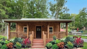 A wooden cabin with a porch, steps, and a front door. - HOT TUB, outdoor movie theater, coffee bar,Fire pit, BBQ, pavilion & LAKE VIEWS! (Greentown)