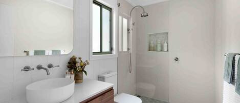 A modern bathroom with a large sink, a toilet, and a shower area.