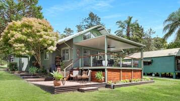 A two-story house with a covered porch, outdoor seating, and a garden.
