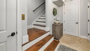 A staircase with wooden steps leading to a landing, a white door, and a small wooden cabinet with a lamp on top. - 7-bedroom cottage in fabulous St. Simons Island with lounge pool, WiFi, AC. (St. Simons Island)