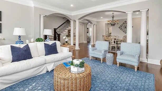 A spacious living room with a white sofa, blue patterned rug, and a ceiling fan. - 7-bedroom cottage in fabulous St. Simons Island with lounge pool, WiFi, AC. (St. Simons Island)