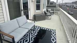 A balcony with a gray sofa, a black coffee table, and a patterned rug.