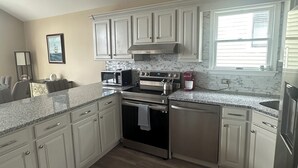A modern kitchen with white cabinets, a stainless steel range, and a granite countertop.