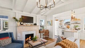 A spacious living room with a fireplace, a dining area, and a kitchen. -  Avail  this Dec 1st  2026. (Laguna Beach)