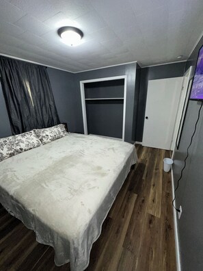A bedroom with a bed, a wardrobe, a door, and a ceiling light.