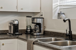 Ett kök med en kaffebryggare, en mixer och en kaffekanna på bänkskivan.